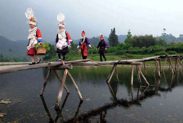Taijiang county, China: Ethnic Miao girls walk across a river to visit relatives to celebrate the Sisters festival