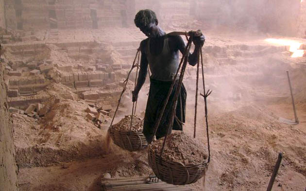 An Indian laborer carries dust and ash at a brick factory 