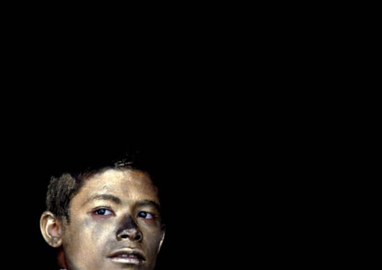 A boy has his face covered with silver powder as he celebrates Holi