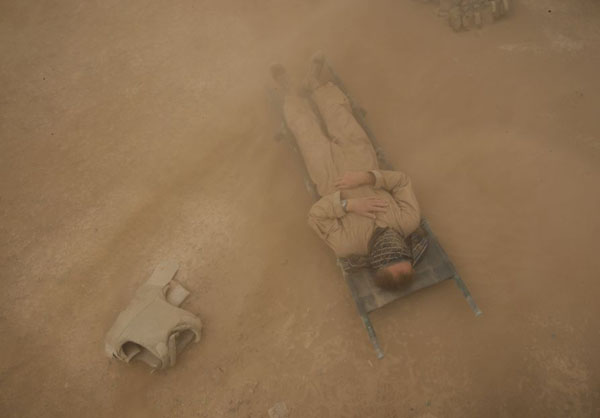 Helmand province, Afghanistan: A US Marine ies on a stretcher behind his vehicle as he tries to take shelter from a sand storm