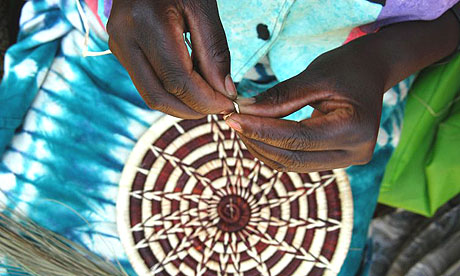 A woman from the Rwandan town of Mayange weaves a basket to be sold by Macy's in the United States