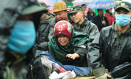 A mother mourns a Chinese soldiers carry the body of her child who was killed when a school building collapsed during the earthquake in Dujiangyan, China.