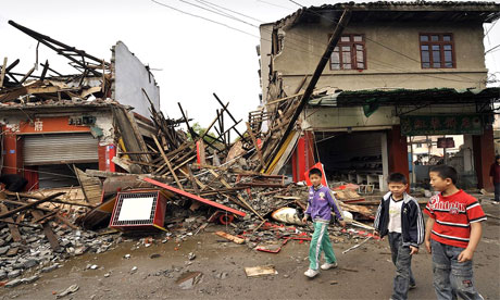 Children walk in front of destroyed buildings in Dujiangyan