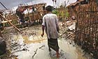 A man walks towards the remains of his home in a village at the outskirts of Yangon, Burma