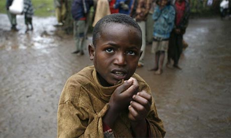 A boy shivers in the rain as villagers carry sacks of maize received from the Red Cross in the Volayta region of southern Ethiopia