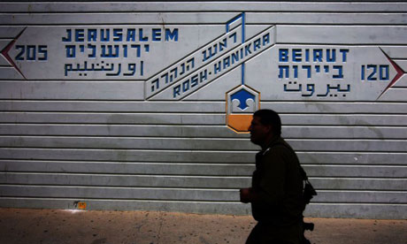An Israeli soldier at a border crossing point showing the distance to Jerusalem and Beirut