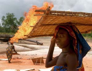 Women dry tapioca beside flames from Shell's Utorogu flow station in the Niger Delta March 5, 2006