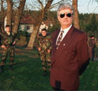 Former Bosnian Serb leader Radovan Karadzic stand surrounded by guards