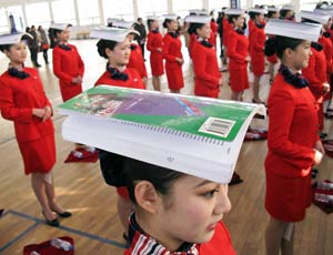 Chinese students balance books on their heads during an etiquette training class