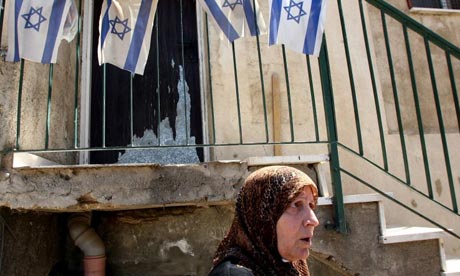 Palestinian Fawzia al-Kurd walks past a house displaying Israeli flags in the neighbourhood of occupied east Jerusalem