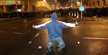 A protester kneels to face police during a second night of rioting in Budapest