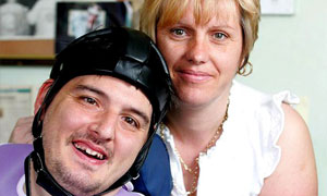 Simon Stevens, a disability consultant who has cerebral palsy, with his personal assistant Flora Lloyd at home in Coventry